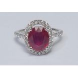 A ruby and diamond cluster ring, larger oval mid red ruby measuring approx 10.37mm x 8.76mm x 5.