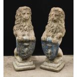 A pair of reconstituted stone heraldic lions, each grasping a shield, stepped bases, 74cm high, 26cm