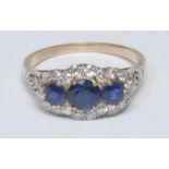 A sapphire and diamond cluster ring, central round deep blue sapphire, flanked by a smaller sapphire