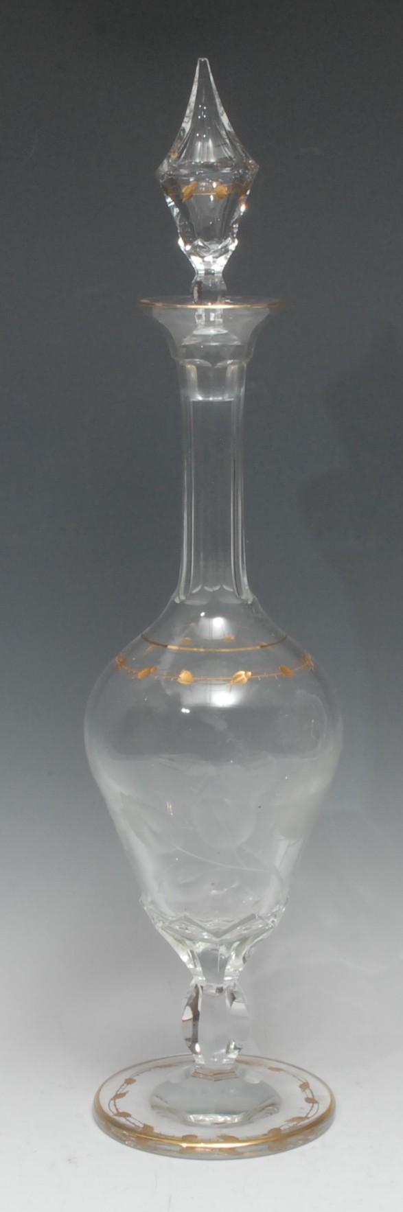 A Moser glass ogee pedestal decanter, cut and etched with roses and leafy stems, below a