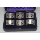 A set of six George V silver napkin rings, each pierced with leafy scrolls between egg-and-dart