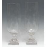 A pair of glass storm lanterns, each decorated with eight-pointed stars, stepped square bases,