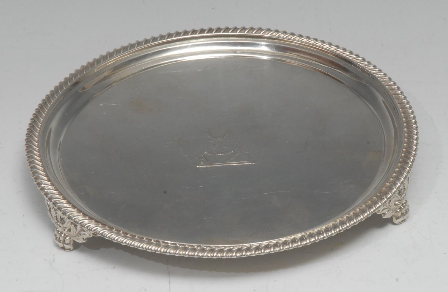 A George IV silver circular waiter, gadrooned border, crested field, shell and acnthus paw feet,