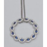 A contemporary sapphire and diamond circular pendant necklace, circular body inset with twelve round