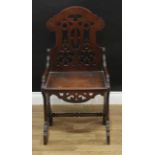 A Reformed Gothic oak hall chair, shaped arched back, sides and apron, pierced with tracery, boarded