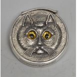 A silver novelty ciircular vesta case, cast to recto and verso with the face of a cat, glass eyes,