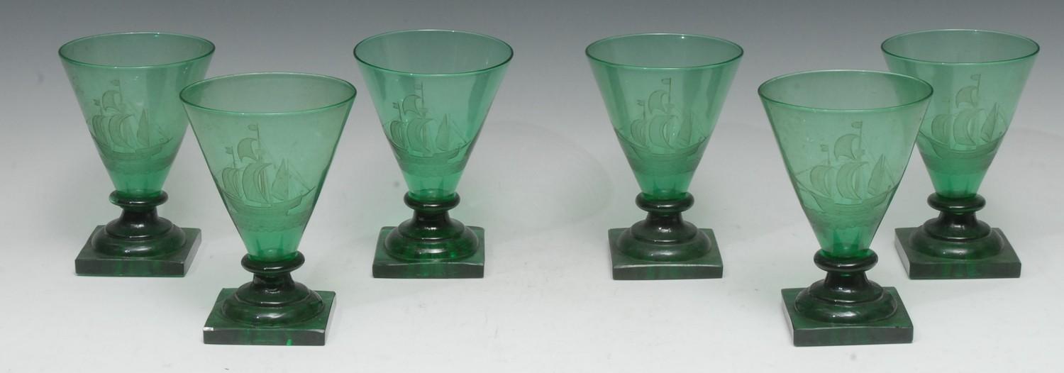 A set of six Art Deco green glass drinking glasses, each conical-shaped bowl engraved with a
