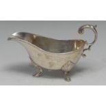 A George VI silver sauce boat, of George III design, acanthus-capped flying scroll handle, pad