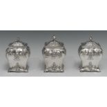 A set of three early George III Rococo silver tea caddies, each chased with flowers, stiff leaves