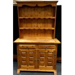 A modern pine dresser, outswept cornice, shaped aprons to shelving, two short drawers over two block