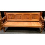 An early 20th century pitch pine settle, four panelled back, shaped arms, turned forelegs. 96.5cm