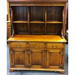 A country oak dresser, stepped cornice, partitioned shelving, shaped uprights, three short drawers