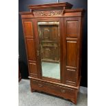 An Edwardian mahogany wardrobe, carved cornice, bevel edge mirrored door flanked by fielded