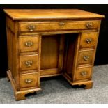 An oak kneehole desk of small proportions, crossbanded top, long drawer over recessed cupboard