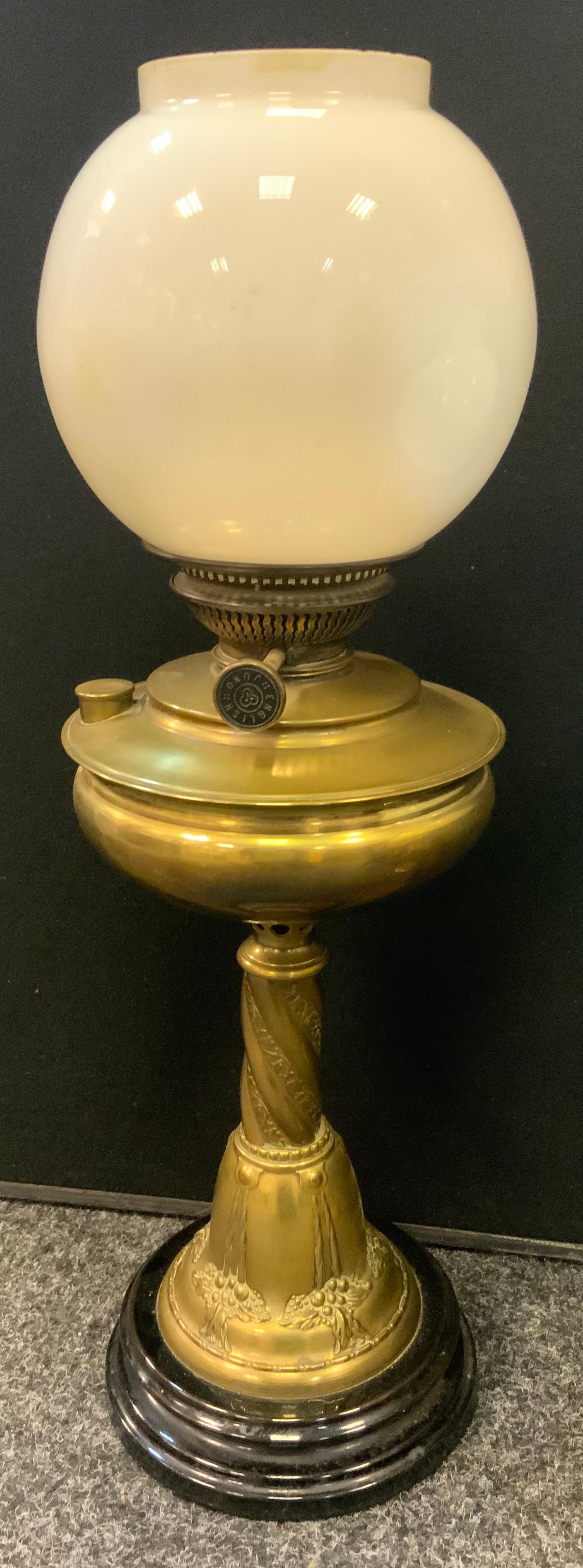 An Art Nouveau brass Juno oil lamp, embossed base and twisting column, opaque glass globular