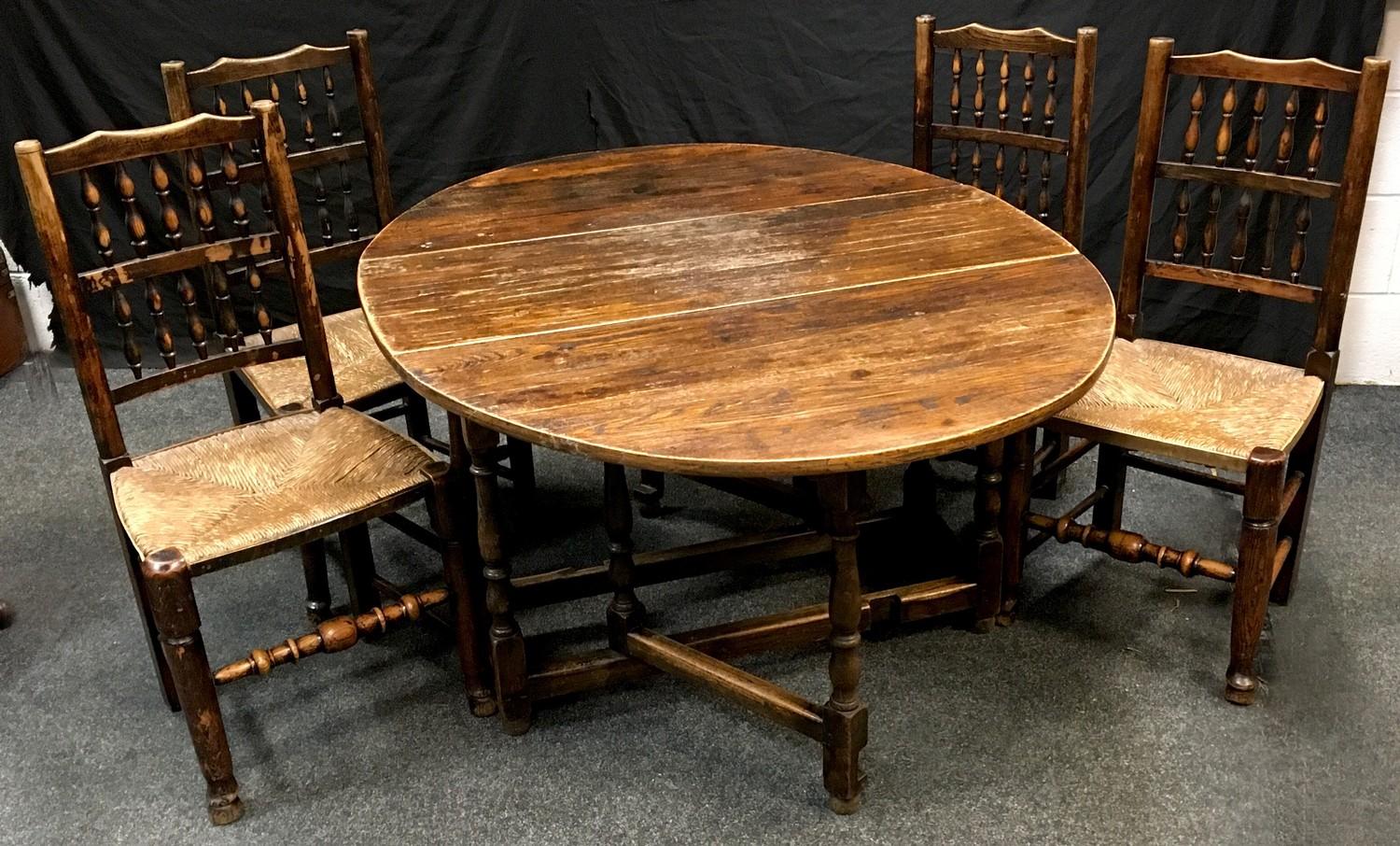 A set of four raffia seated spindle back Lancashire style dining chairs; an oak gate leg table, oval