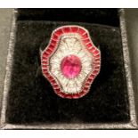 An Art Deco style shield shaped base metal dress ring, set with an arrangement of clear and red