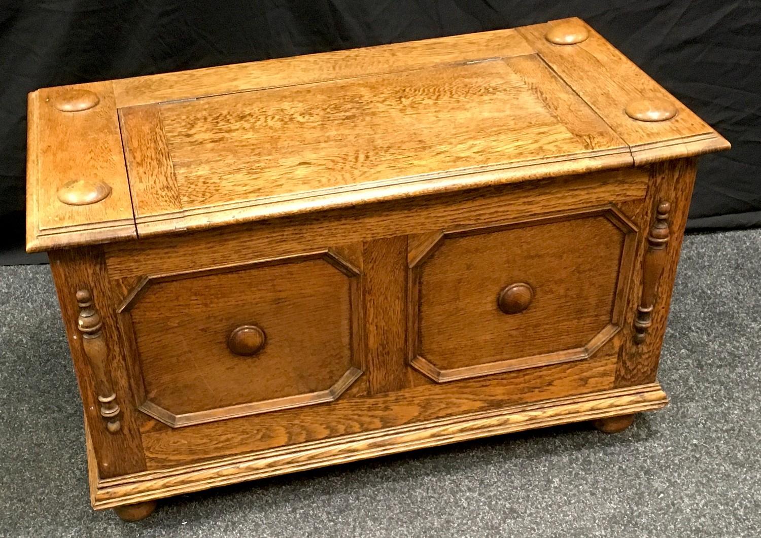 An oak hall seat, hinged cover to top, block fronted panels to front, bun feet. 50cm high x 86cm