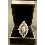 An Art Deco style navette base metal dress ring, set with an arrangement of clear and blue glass