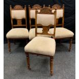 A set of four late Victorian carved walnut dining chairs, carved top, cream upholstered back and