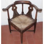 A George II oak corner elbow chair, the inverted vasular splat pierced with ?spades?, drop-in rush