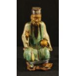 A Chinese celadon glazed figure, of an elder holding a peach, 19cm high