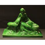 A French 'Art Deco' green glazed model of reclined lady, she sits with a basket to one side and a