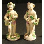 A pair of Bow figures, of allegorical putti, each with a basket of flowers, and wearing floral