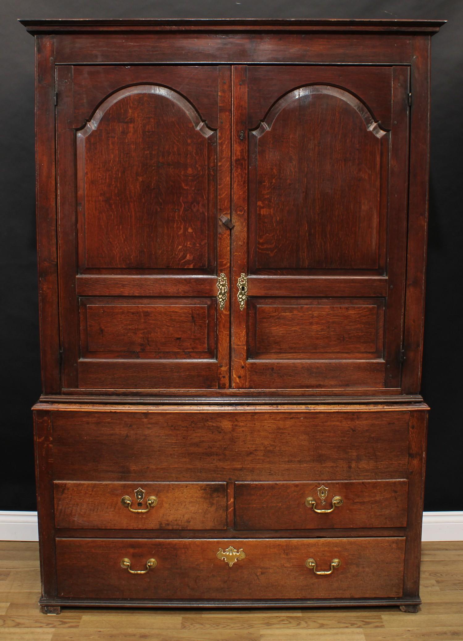 A George III oak housekeeper's or press cupboard, shallow outswept cornice above a pair of raised