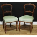 A pair of late Victorian walnut balloon-back boudoir chairs, each fluted cresting rail carved with a