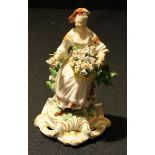 A rare Derby Patch Mark figure, Allegorical of Spring, seated holding a basket of flowers, before