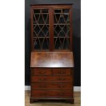 A George III Revival mahogany bureau bookcase, shallow outswept cornice above a pair of glazed doors