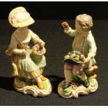 A pair of Bloor Derby figures, Seated Boy and Girl with Fruit and Flowers, painted in polychrome
