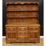 A George III style oak dresser, outswept cornice above a shaped apron and two plate racks, the