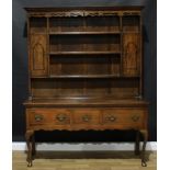 A George II style oak dresser, outswept cornice above three plate racks, a pair of open niches and
