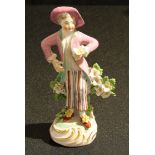 A Derby Patch Mark figure, of a boy, holding a flower posy, wearing a pink hat and waistcoat,