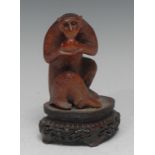 A Japanese novelty hardwood carving, of a comical monkey eating a ripe peach, inset glass eyes, 10.