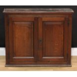 A George III oak wall hanging cupboard, shallow moulded cornice above a pair of raised and fielded