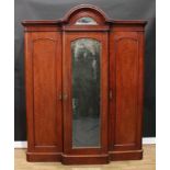 A Victorian mahogany three-door wardrobe, arched outswept cornice set with a bevelled demilune