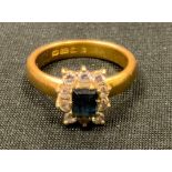 A 22ct gold sapphire and diamond cluster ring, the central claw set emerald cut blue sapphire