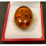 A large yellow metal dress ring mounted with an oval baltic amber cabochon , insect wing inclusions,