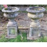 A pair of reconstituted stone planters and stands. 74cm high. This lot must be collected from S44