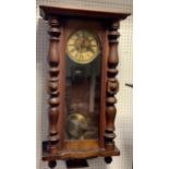 A Vienna wall clock, enameled chapter ring, Roman numerals, glazed door, flanked by turned pilasters