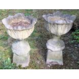 A pair of reconstituted stone planters and stands. 82cm high x 49cm diameter. This lot must be