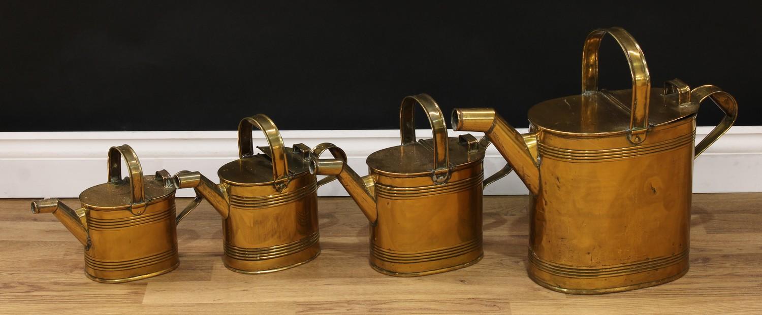 A graduated set of four 19th century brass hot water cans, the largest 39cm high over handle (4)