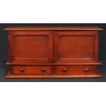 An Edwardian mahogany desk top cabinet, oversailing top above a pair of doors enclosing stationery
