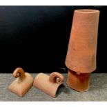 A terracotta chimney pot 88cms high; a pair of decorative scroll ridge tiles (3)