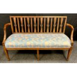 An Edwardian mahogany two-seater settee, shaped splats, outswept arms, tapered square legs, stuffed