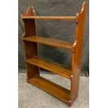 A late Victorian mahogany wall mounting book shelf, four open backed shelves, shaped sides and