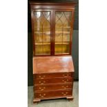 A mahogany bureau bookcase, outswept cornice above a pair of astragal doors enclosing three